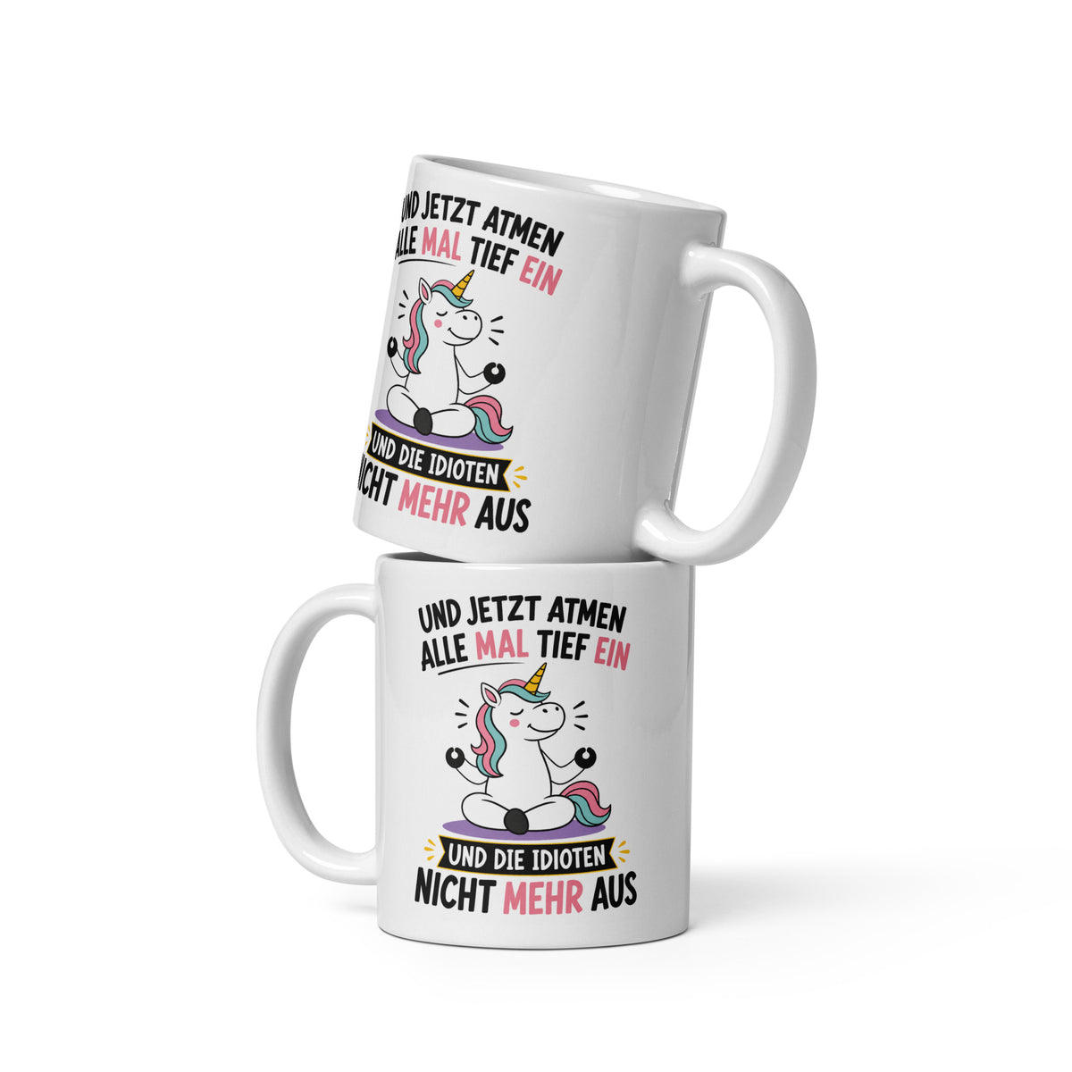 Weiße Keramiktasse mit einem meditierenden Einhorn und dem lustigen Spruch „Und jetzt atmen alle mal tief ein und die Idioten nicht mehr aus“ in schwarzer und pinker Schrift.