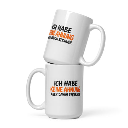 Lustige Tasse mit dem Spruch „Ich habe keine Ahnung, aber davon reichlich.“ in weißer und gelber Schrift auf schwarzem Hintergrund.