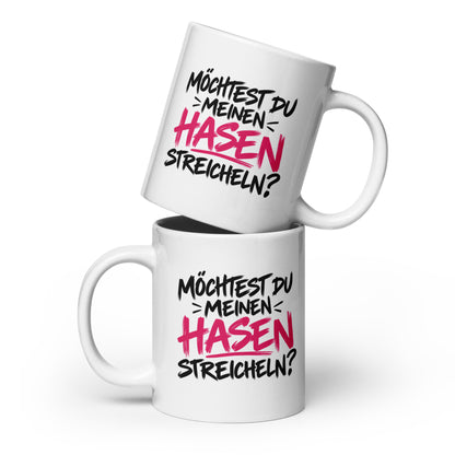Lustige weiße Tasse mit dem frechen Spruch „Möchtest du meinen Hasen streicheln?“ in schwarzer und pinker Schrift.